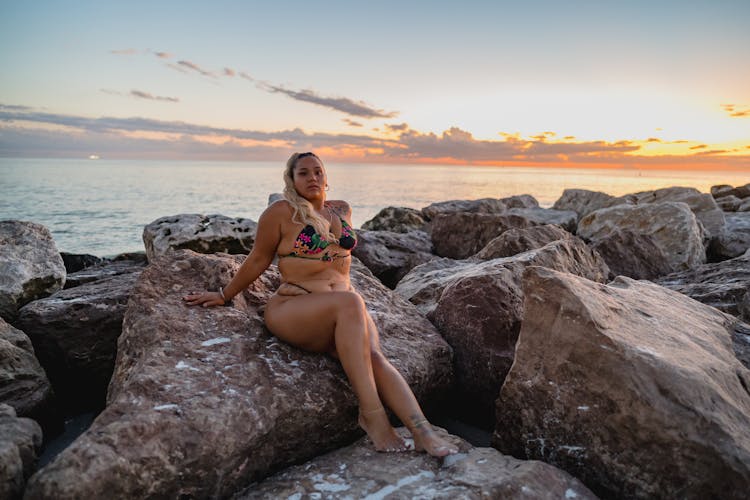 A Woman In Bikini Sitting On Big Rock