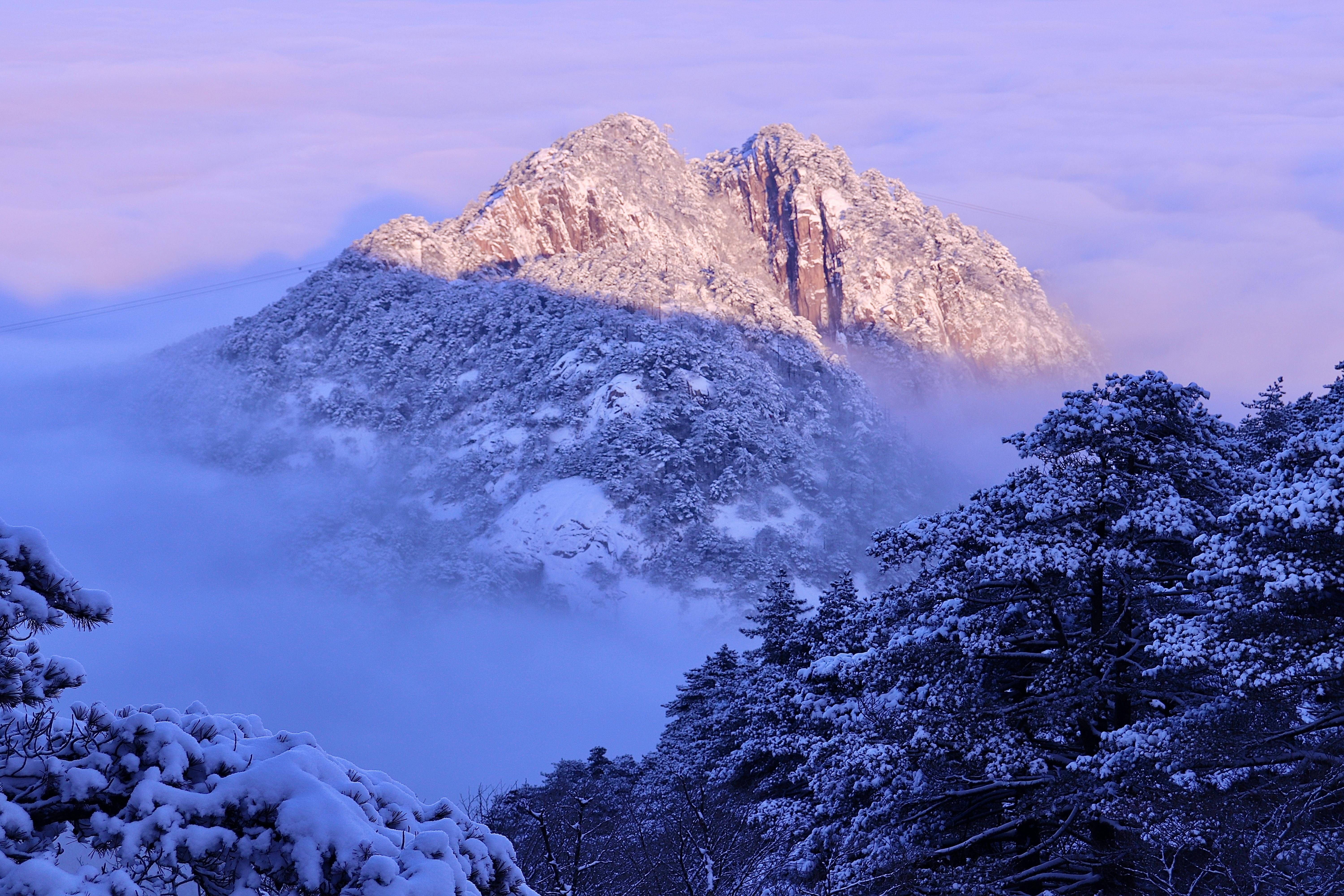 Prescription Goggle Inserts - A breathtaking view of a snow-covered mountain peak enveloped in mist at sunrise, exuding a serene winter atmosphere.