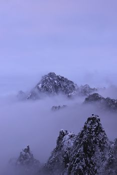 A breathtaking view of snow-capped mountains shrouded in mist, capturing nature's tranquil beauty.