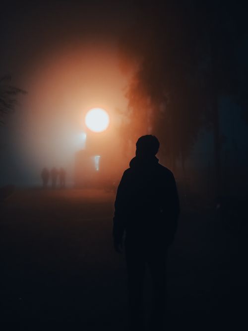 Free A lone silhouette stands against a glowing moonlit foggy background, creating a mysterious atmosphere. Stock Photo