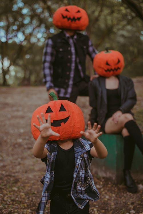 People Wearing Carved Pumpkins Over Their Head