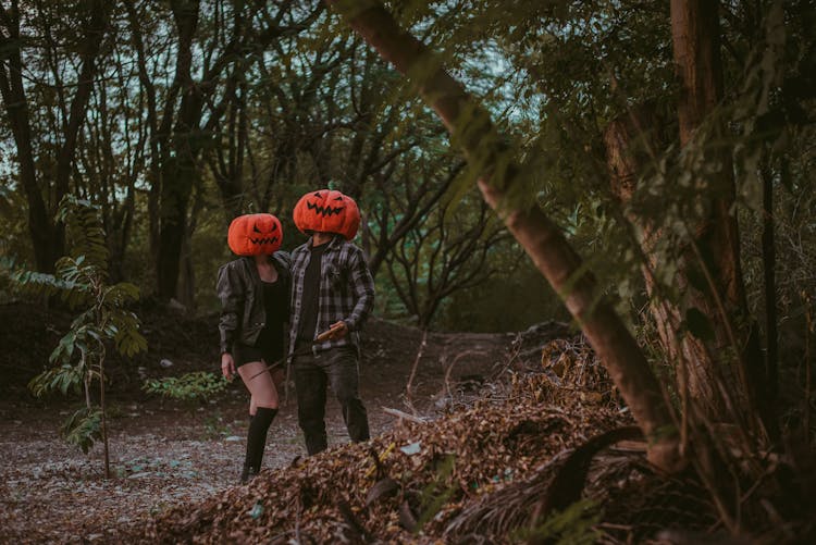 Couple Wearing Pumpkin Mask In The Middle Of Forest