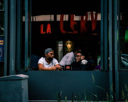 Free Two men sit and chat at a window table of a stylish urban café. Stock Photo
