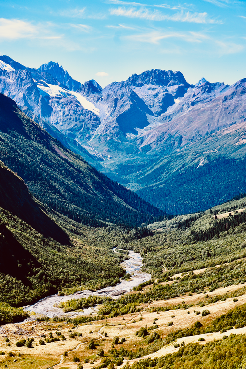 Free Breathtaking mountain range with a river flowing through a lush valley. Stock Photo