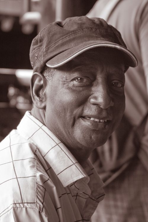 Free Sepia-toned close-up portrait of a smiling man wearing a cap, outdoors in China. Stock Photo