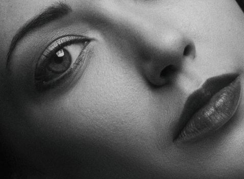 Artistic close-up black and white portrait showing the details of a woman's eye, nose, and lips.