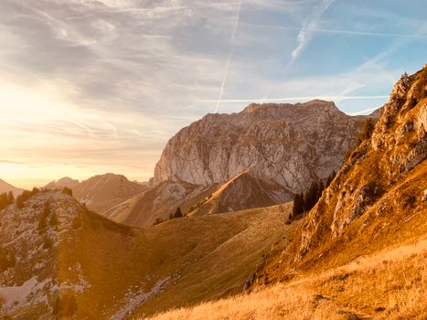 Stunning mountain landscape with vibrant autumn colors at sunrise, featuring clear blue skies and dramatic rock formations.