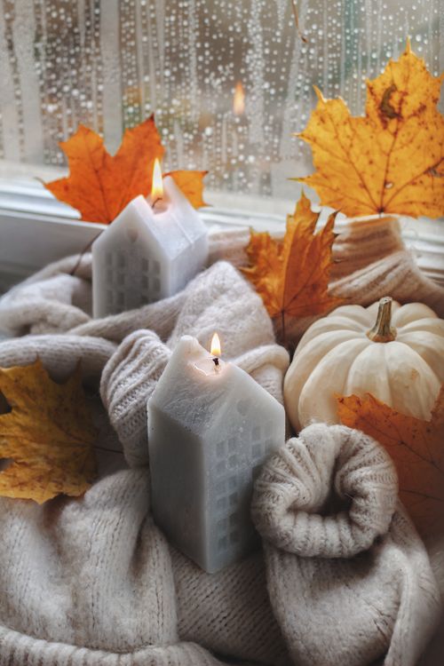 Free Warm autumn scene with glowing candles, knitwear, and leaves by the window. Stock Photo
