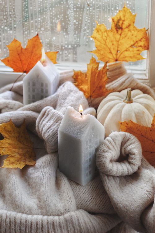 Free Warm cozy autumn scene with candles, leaves, and pumpkin on windowsill. Stock Photo