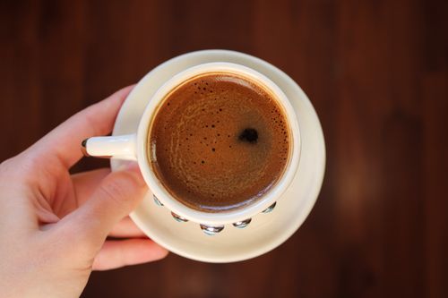 Free Top view of a freshly brewed espresso cup held by hand, perfect for coffee enthusiasts. Stock Photo