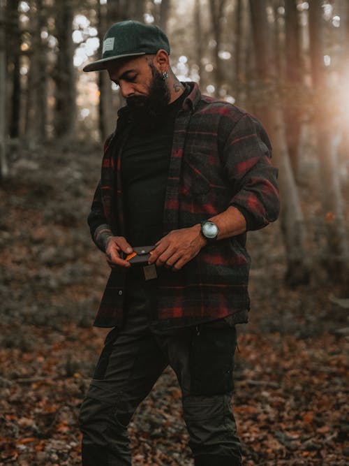 Photo of a Man in Plaid Shirt and Cap Taken in Forest
