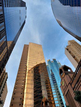A low-angle shot capturing the dynamic skyscrapers of Hong Kong against a clear blue sky.