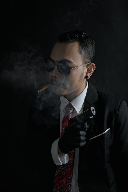 Man Smoking Tobacco While Holding a Gun