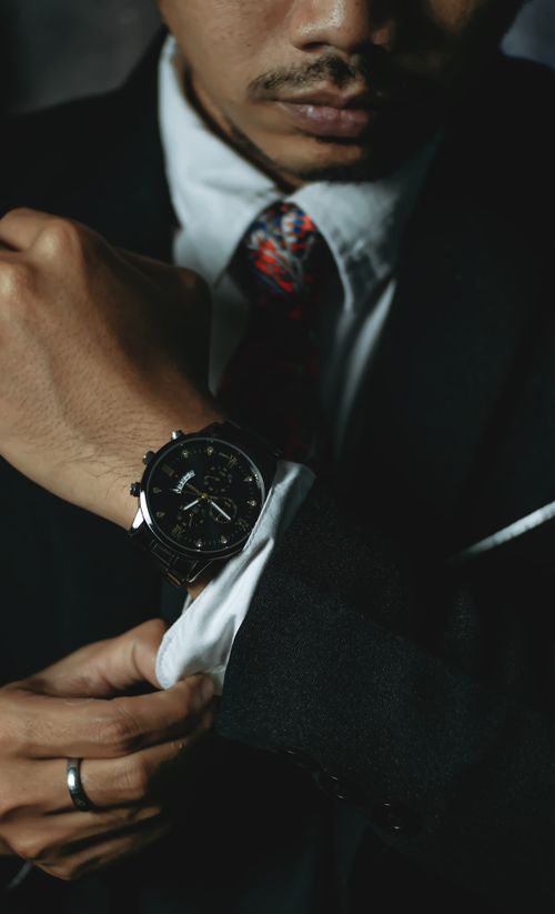 Free Close-up of a man in a suit adjusting his wristwatch, showcasing elegance and preparation. Stock Photo