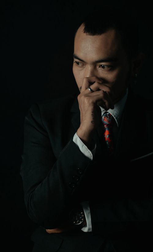 Free Thoughtful businessman in dark business attire, contemplating with hand on chin. Stock Photo