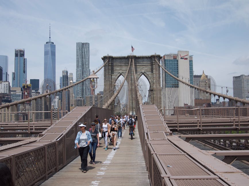 View of the Brooklyn Bridge with pedestrians, set against the iconic New York City skyline.