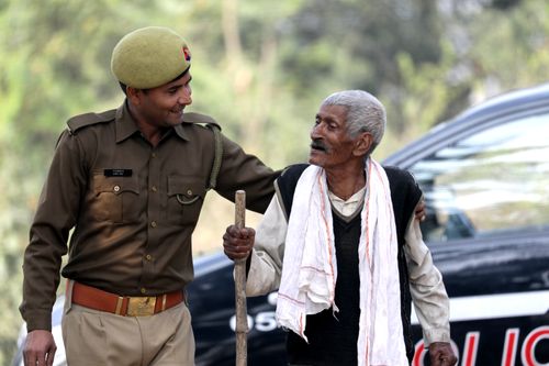 Free A compassionate police officer helps an elderly man walk, showcasing community support. Stock Photo