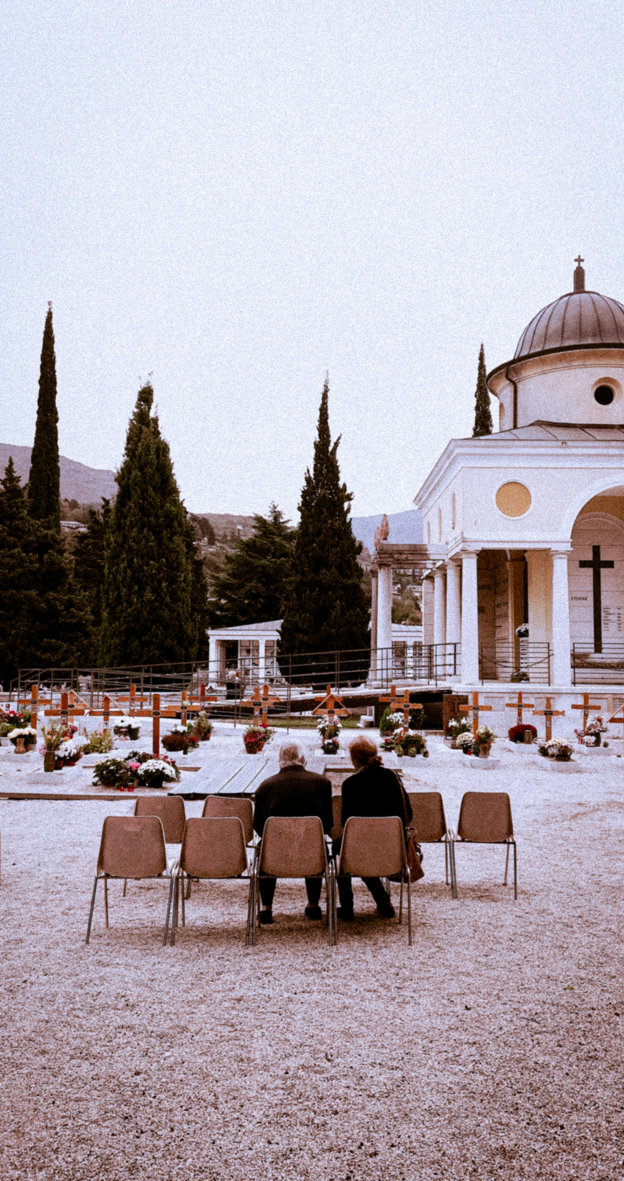 Visitors sitting outside a mausoleum in Rovereto, highlighting Italian architecture.