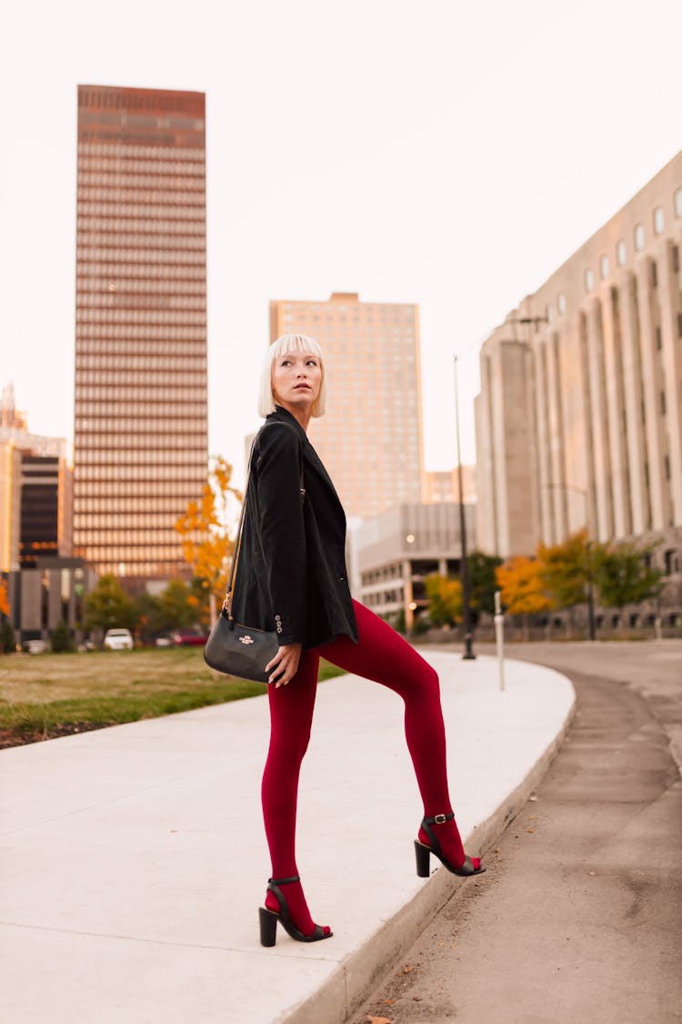 Woman Posing In Red Tights And Black Jacket In Office District 