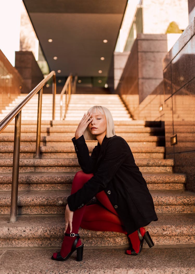 Blonde Fashion Model Crouching By Stairs In Office Building