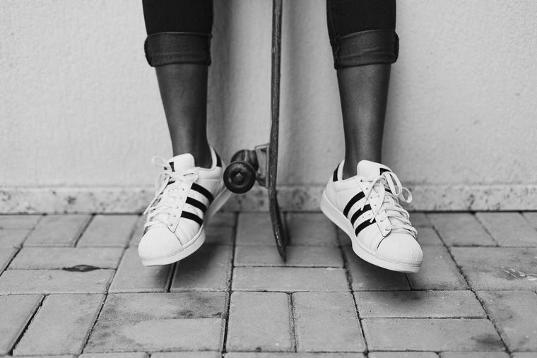 Sneakers and a skateboard on the pavement — photo by Karyme França on Pexels