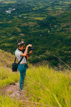 Female photographer capturing a scenic view with lush greenery, representing travel and adventure.