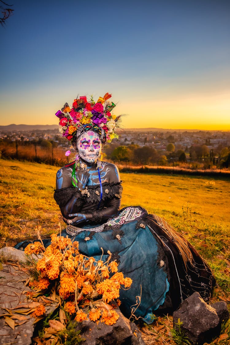 A Woman With Face Paint Wearing An Off-Shoulder Dress And A Headdress