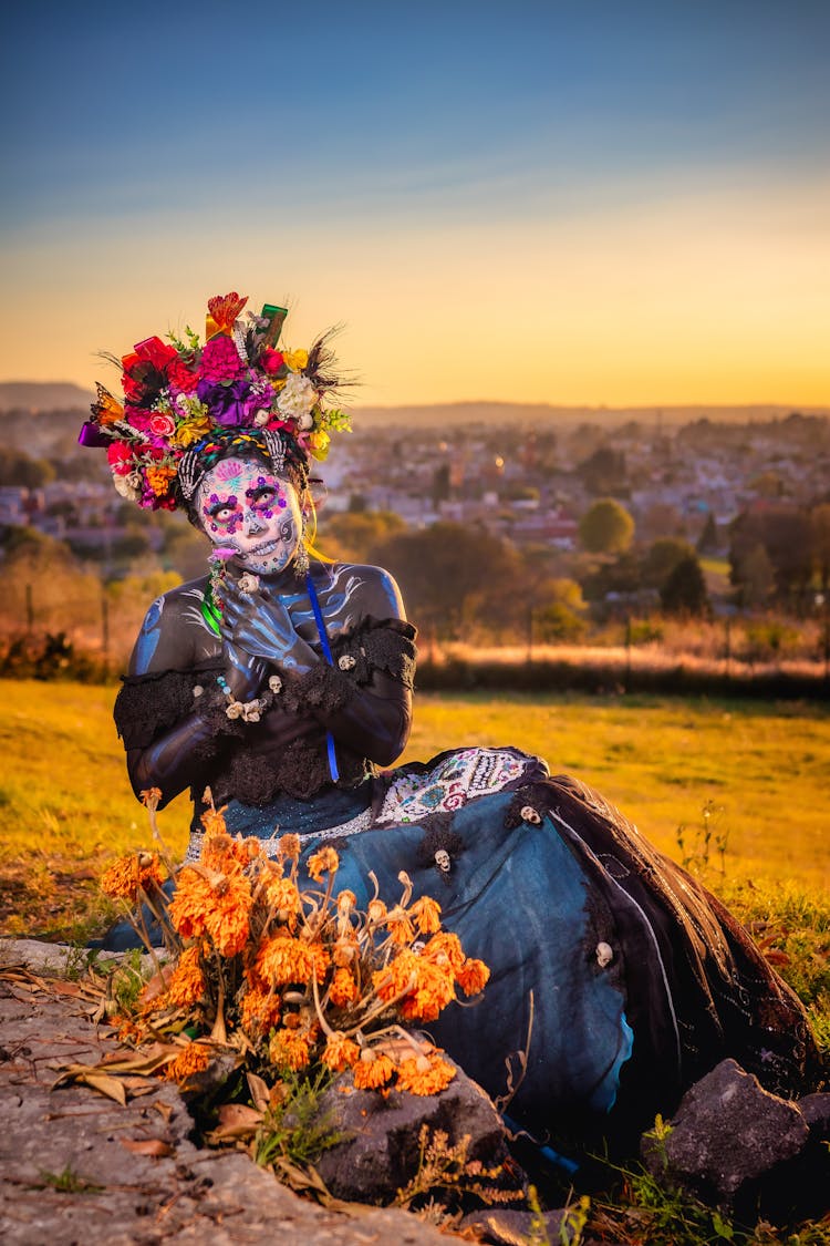 A Woman With Face Paint Wearing An Off-Shoulder Dress And A Headdress