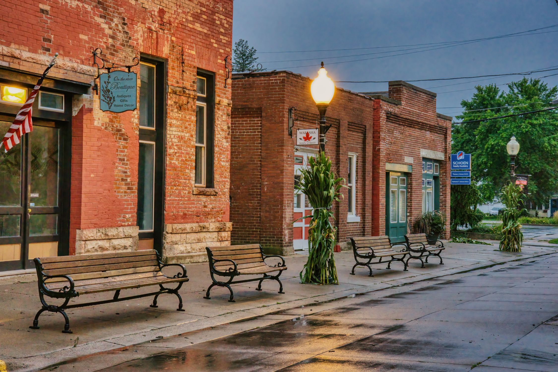 Wide sidewalks, rustic benches, and brick storefronts define a classic small-town Main Street.