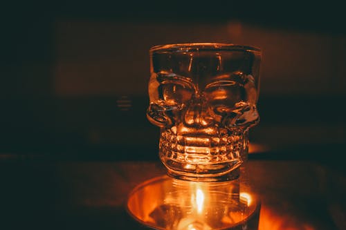 Close-up of a Glass in a Shape of a Skull and a Candle 