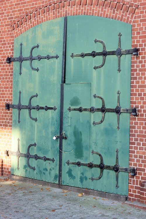 A Green Metal Door on Brown Brick Wall 