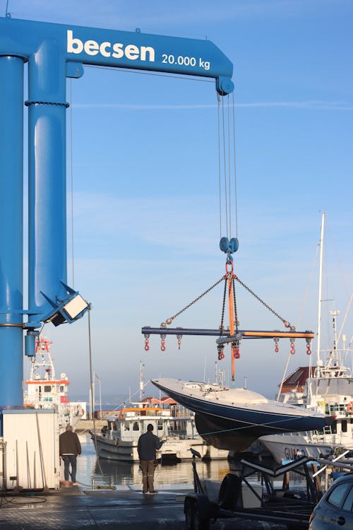 Photo of a Crane Lifting a Boat in a Harbor