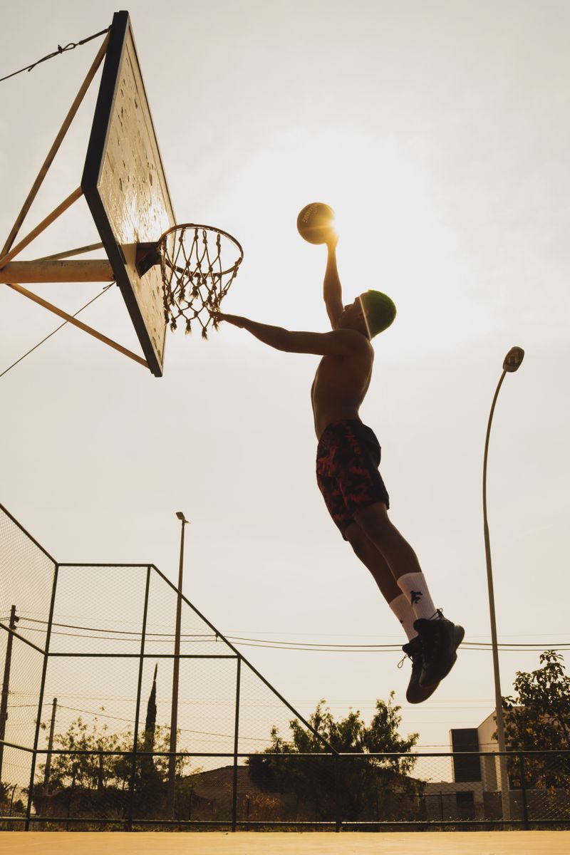 Silhouette of a basketball player dunking on an outdoor court at dusk — photo by samuel reis on Pexels