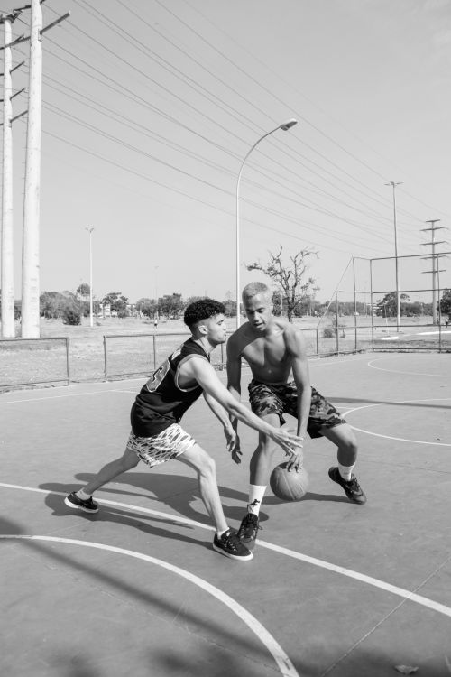 Free Two men playing basketball on an outdoor court in black and white. Stock Photo