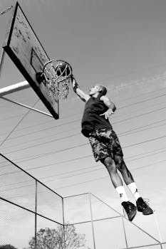 Energetic outdoor basketball dunk captured in striking black and white.