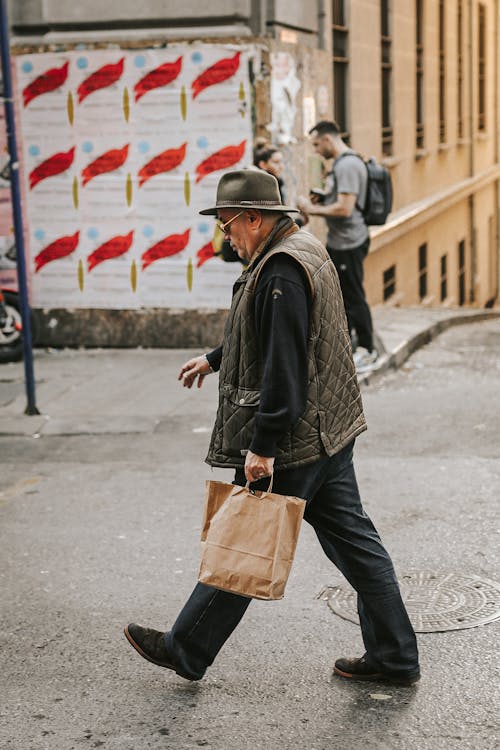 Photo of a Man Holding a Paper Bag While Walking