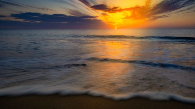 Captivating beach sunset with vibrant colors and gentle waves during golden hour.