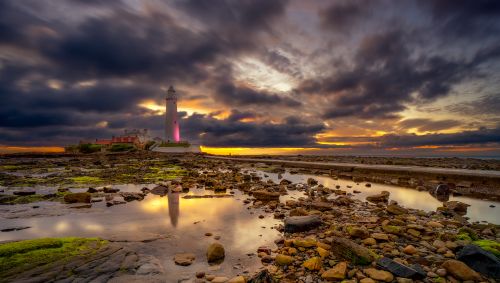 Free Capture of St Mary's Lighthouse amidst rocky shore at stunning sunset. Stock Photo