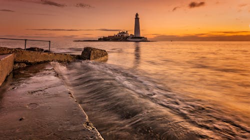 Photo of White Lighthouse on the Sea during Sunset