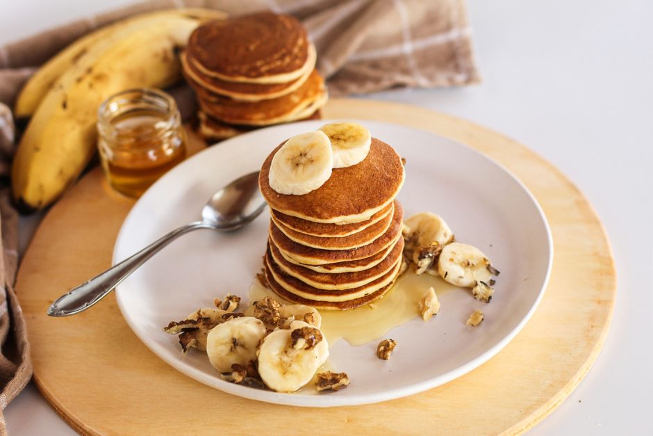 Stack of banana pancakes drizzled with honey and walnuts, perfect breakfast delight.