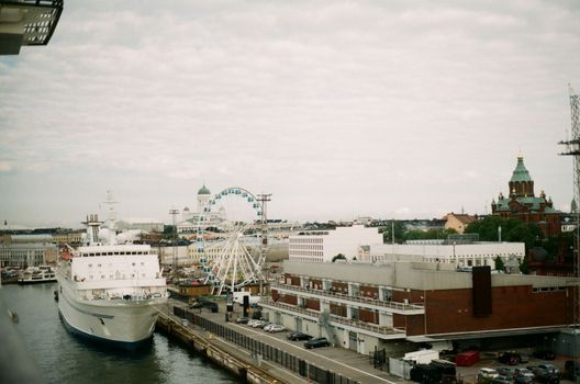 Aerial view of Helsinki port featuring a docked ship and a Ferris wheel with city landmarks.