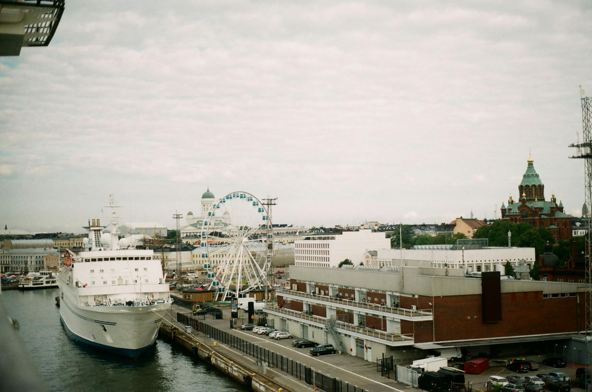 Aerial view of Helsinki port featuring a docked ship and a Ferris wheel with city landmarks.