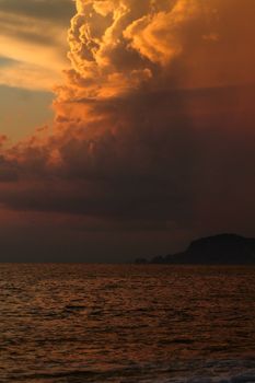 A breathtaking view of dramatic storm clouds illuminated by the sunset over a calm ocean.