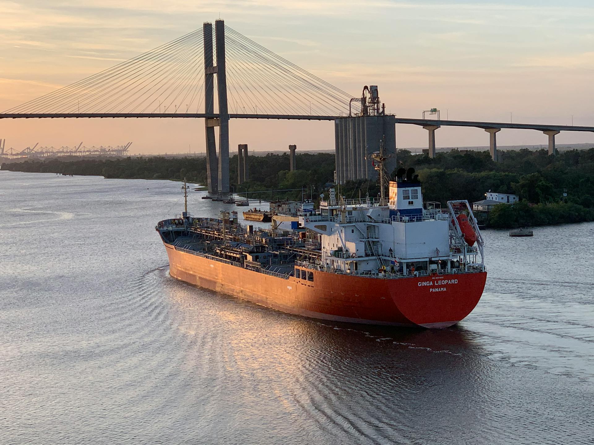 A cargo ship sails near the Talmadge Memorial Bridge in Savannah, Georgia, during sunset.