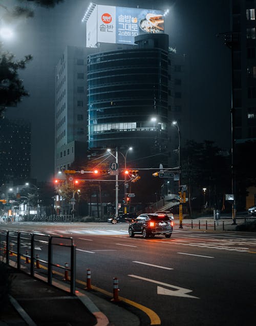 Cars on Road Near High Rise Buildings during Night Time