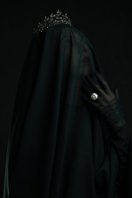 A mysterious portrait of a veiled woman with a crown captured in a dark, moody setting.