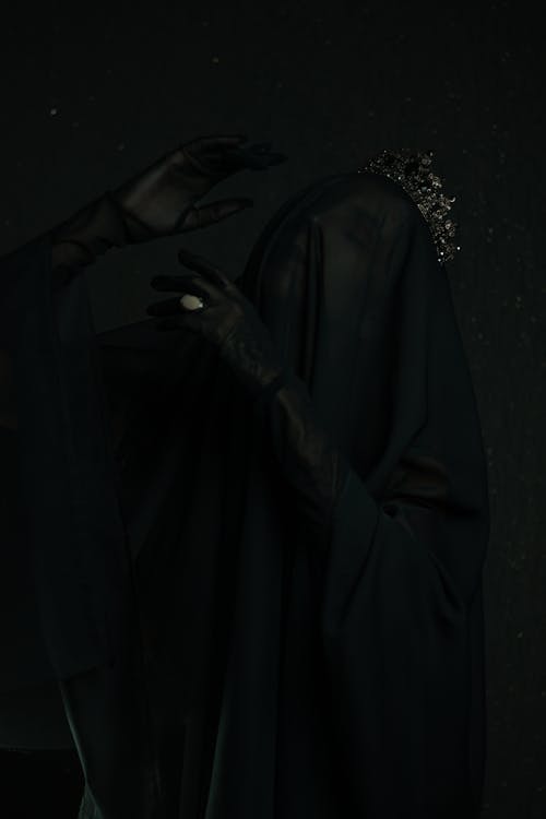 Dark Photo of a Woman Wearing a Black Costume and a Veil Covering Her Face