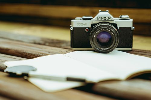 Free Classic Minolta film camera with a vintage lens on a wooden table, capturing a nostalgic feel. Stock Photo