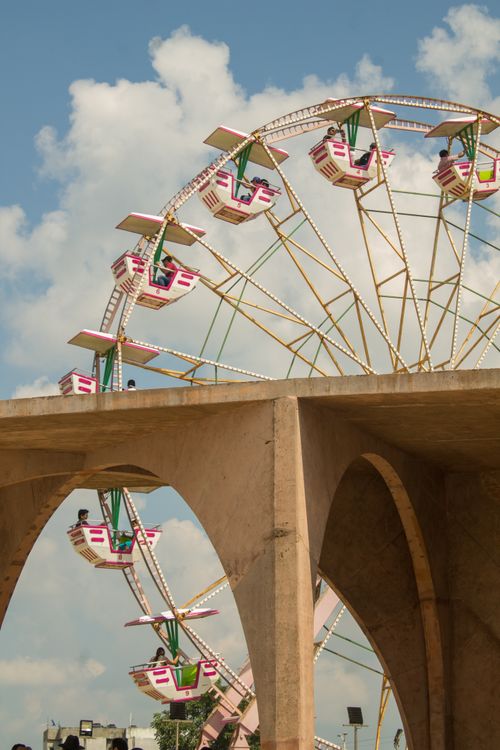 Free Vibrant ferris wheel set against a clear blue sky with fluffy clouds, creating a cheerful and lively atmosphere. Stock Photo