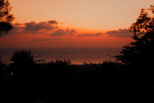 Free A breathtaking view of numerous boats silhouetted against a vibrant sunset over the sea. Stock Photo